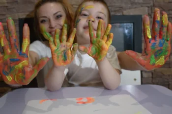 Žena s chlapečkem ukazují pomalované dlaně.