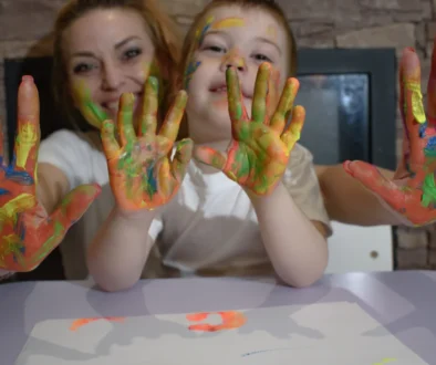 Žena s chlapečkem ukazují pomalované dlaně.