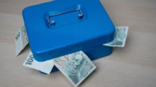 Modrá pokladnička s bankovkami v hodnotě 100 Kč