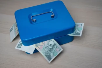 Modrá pokladnička s bankovkami v hodnotě 100 Kč