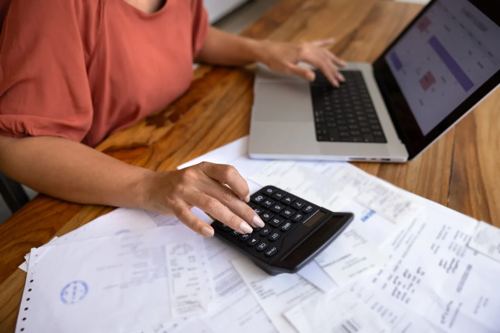 shutterstock_2691943815-2 - Techsvět Žena má na stole papíry, notebook a kalkulačku.