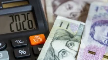 Na stole leží české bankovky v nominální hodnotě pět set, tisíc a dva tisíce korun a kalkulačka