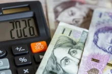 Na stole leží české bankovky v nominální hodnotě pět set, tisíc a dva tisíce korun a kalkulačka
